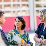 Three people in conversation at a reception.