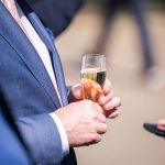 Person holding champagne glass, elegant outfit.