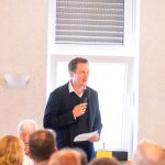 Person speaks into microphone at meeting.