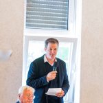 Person holds microphone and speaks in front of audience.