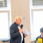 Elderly man speaks with microphone at FDP event.