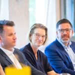 Three people in a meeting, smiling and attentive.