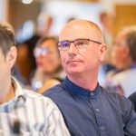 Man with glasses sits concentrated in the audience.
